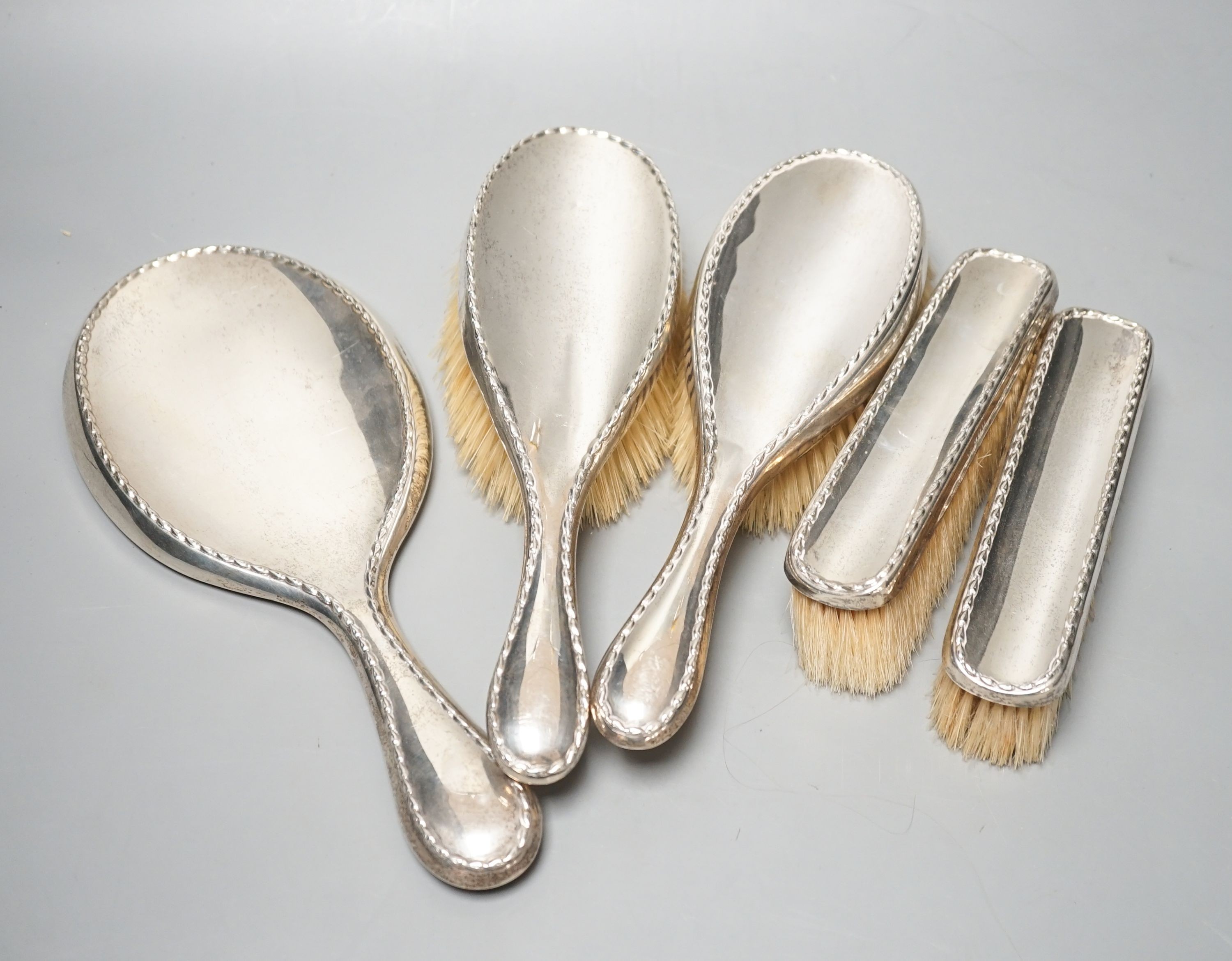 An early 20th century matched five piece silver mounted mirror and brush set.